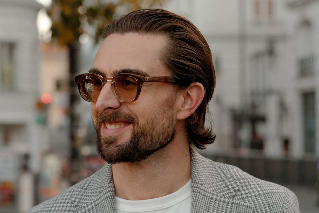 Three quarter view of man smiling wearing thick crystal and amber eyeglasses frame